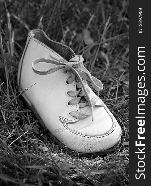 Old white baby boots on grass.