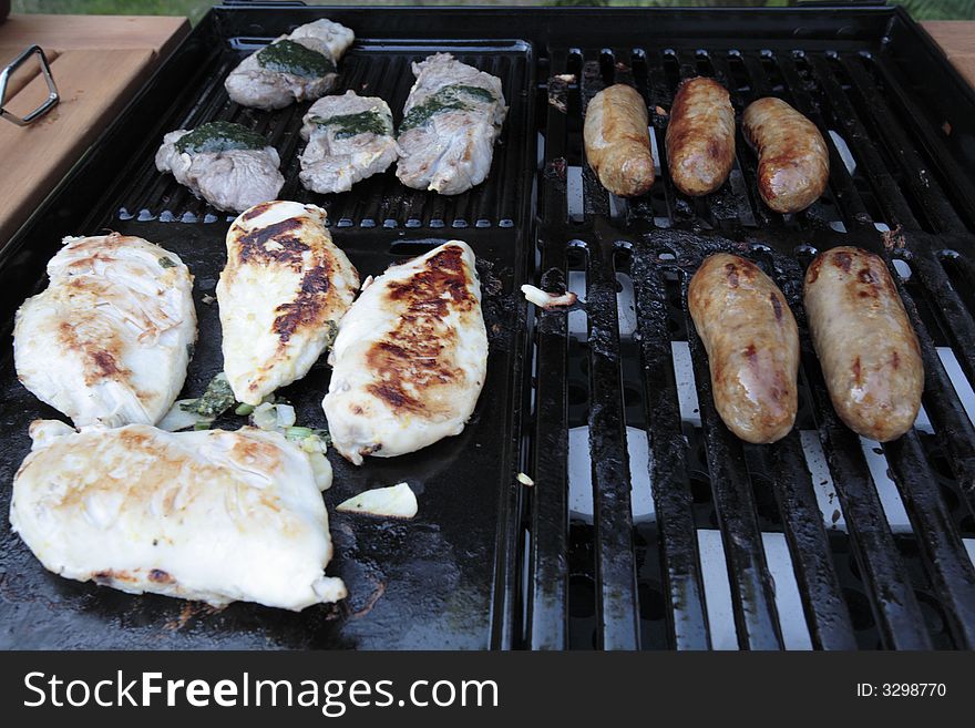 Cooking meat sausages and chicken on a BBQ. Cooking meat sausages and chicken on a BBQ