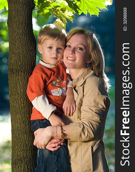 Laughing mother holds son in autumn park