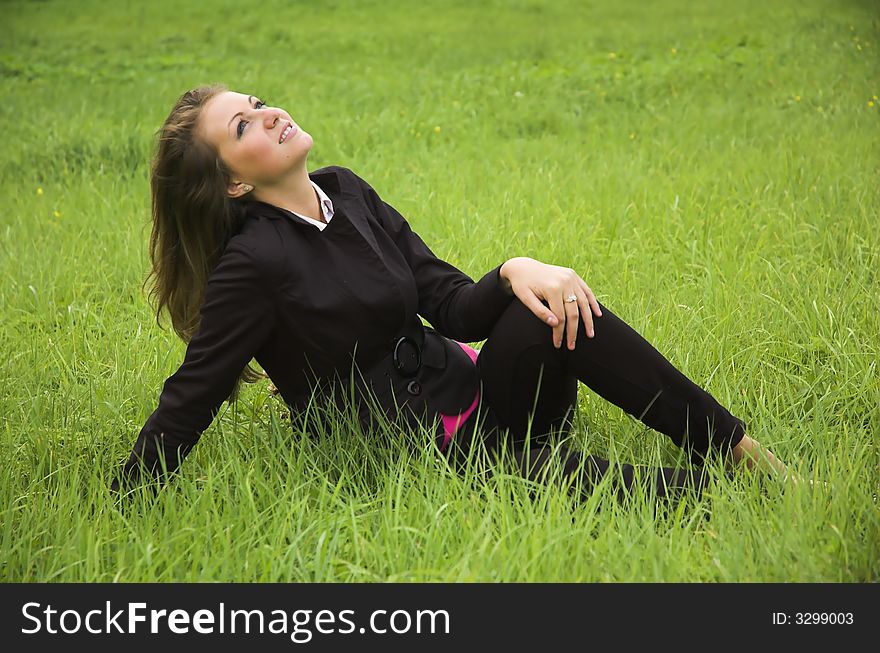 The beautiful girl sits on a green grass. The beautiful girl sits on a green grass