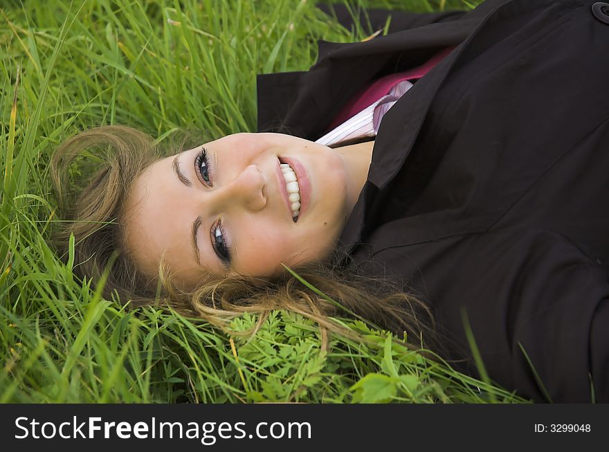 The beautiful girl sits on a green grass. The beautiful girl sits on a green grass