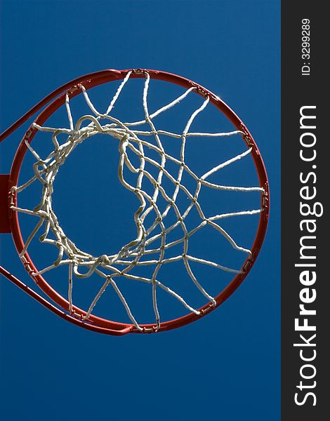 Full basketball hoop as viewed from below against a bright blue sky.