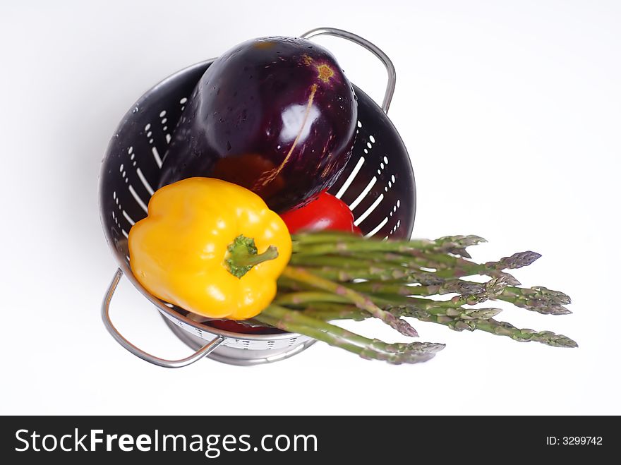 A colander with eggplant,asparagus and peppers. A colander with eggplant,asparagus and peppers