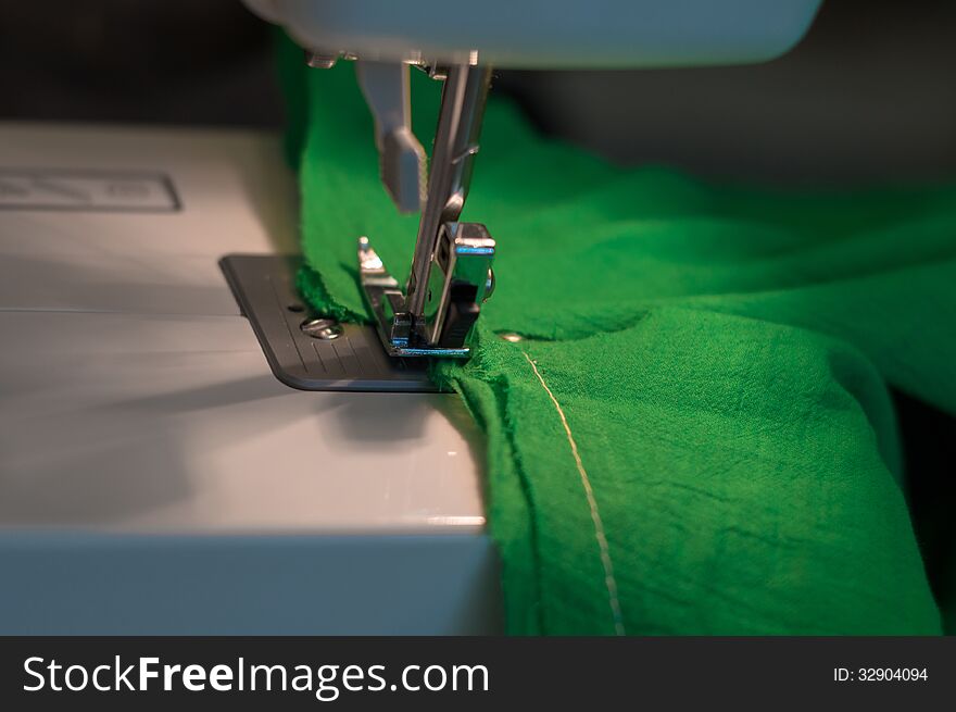 Sewing Process: green textile under the needle in the sewing machine