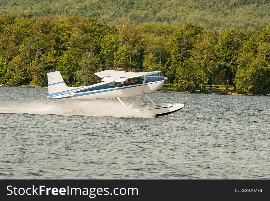 Flying float plane or seaplane taking off at a lake.