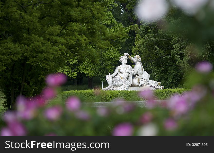 Sculpture of lovers in a park between trees and flowers