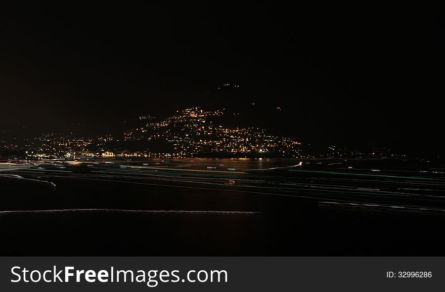 Long exposure on Lugano Lake, the lights of boats navigating the lake leave a luminous trial on the dark surface of the lake. Long exposure on Lugano Lake, the lights of boats navigating the lake leave a luminous trial on the dark surface of the lake