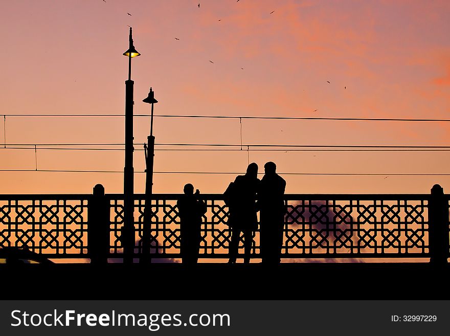 Couple making pictures on the Galata bridge at sunset