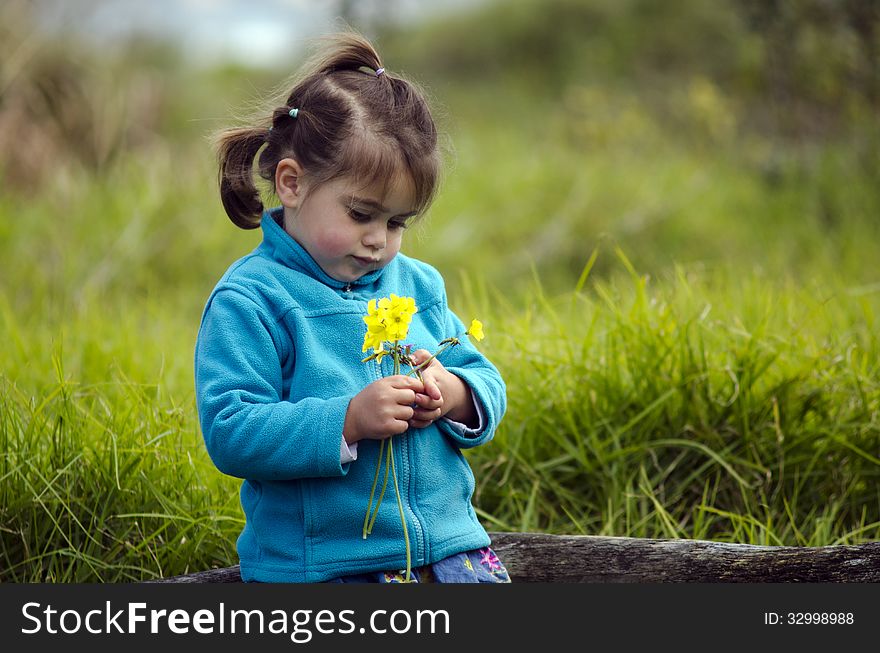 Little girl holds yellow flowers