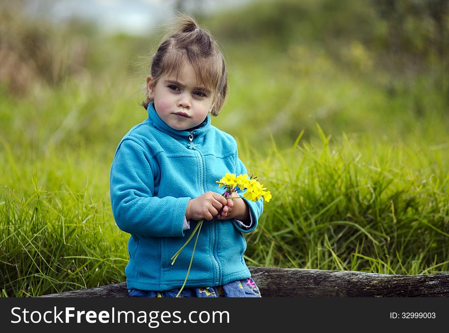 Little girl holds yellow flowers outdoor. (copy space)