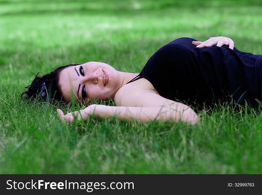 Close-up portrait of an attractive woman outdoors, lying in the grass. Close-up portrait of an attractive woman outdoors, lying in the grass