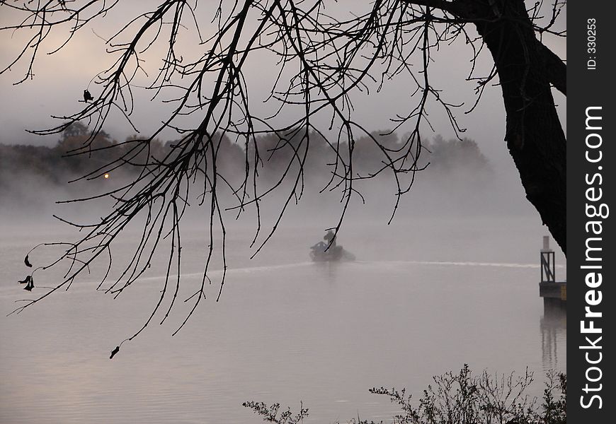 This is a picture of a boat heading out in the early morning on a foggy lake. This is a picture of a boat heading out in the early morning on a foggy lake.