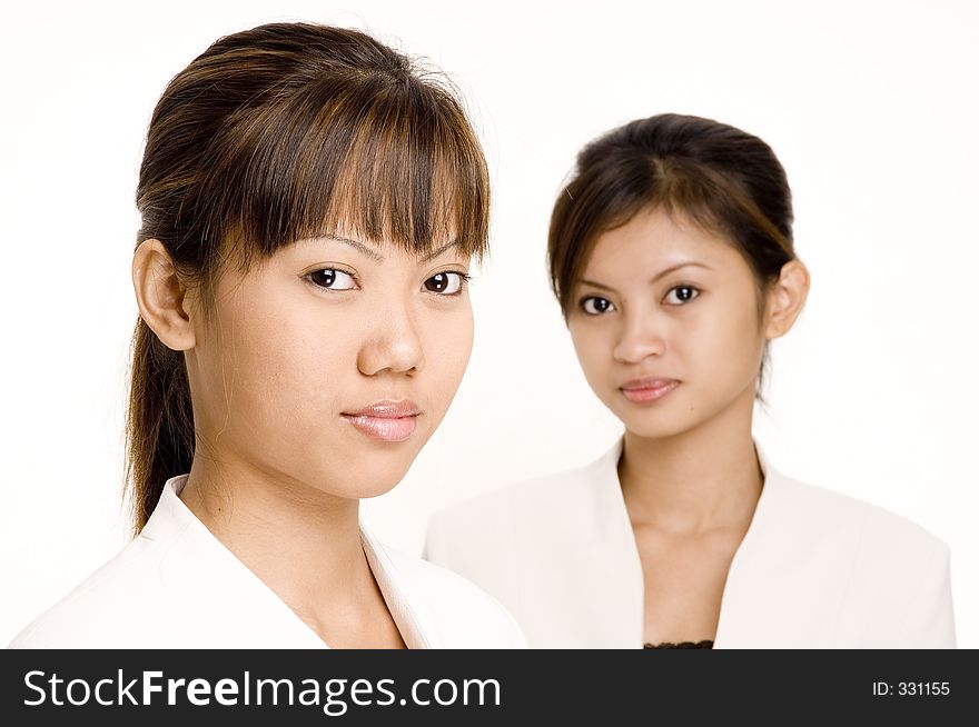 A pair of asian young women in matching business suits. A pair of asian young women in matching business suits