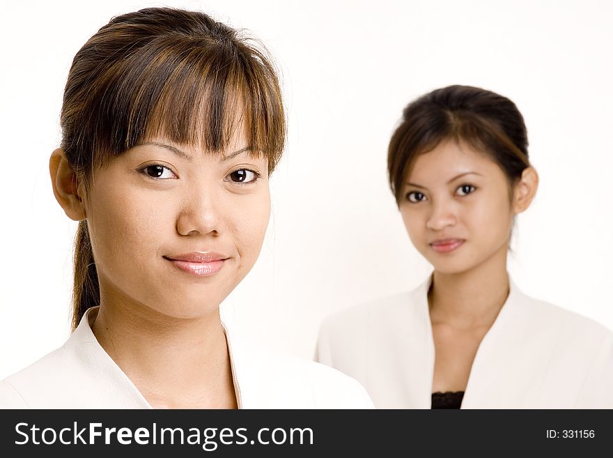 Two smiling asian women in business suits on white background. Two smiling asian women in business suits on white background