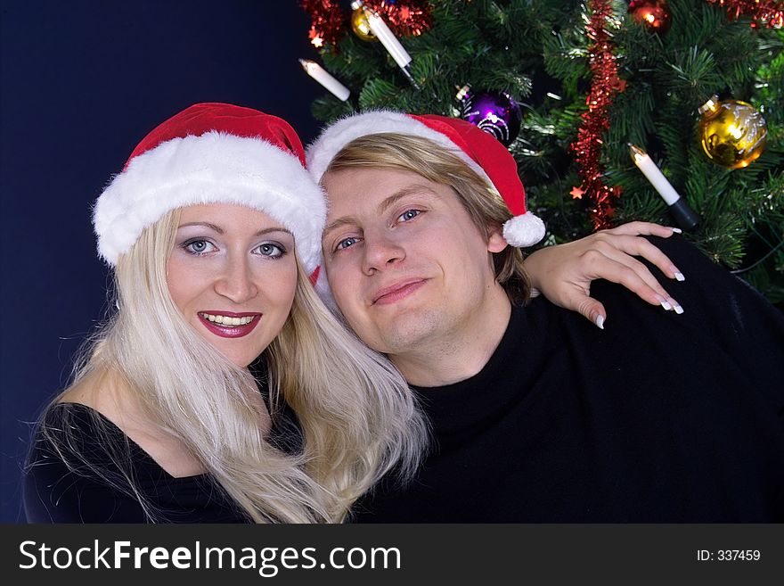 Happy attractive couple in love under christmas tree. Happy attractive couple in love under christmas tree