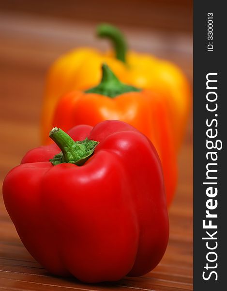 Three colorful peppers on wooden table