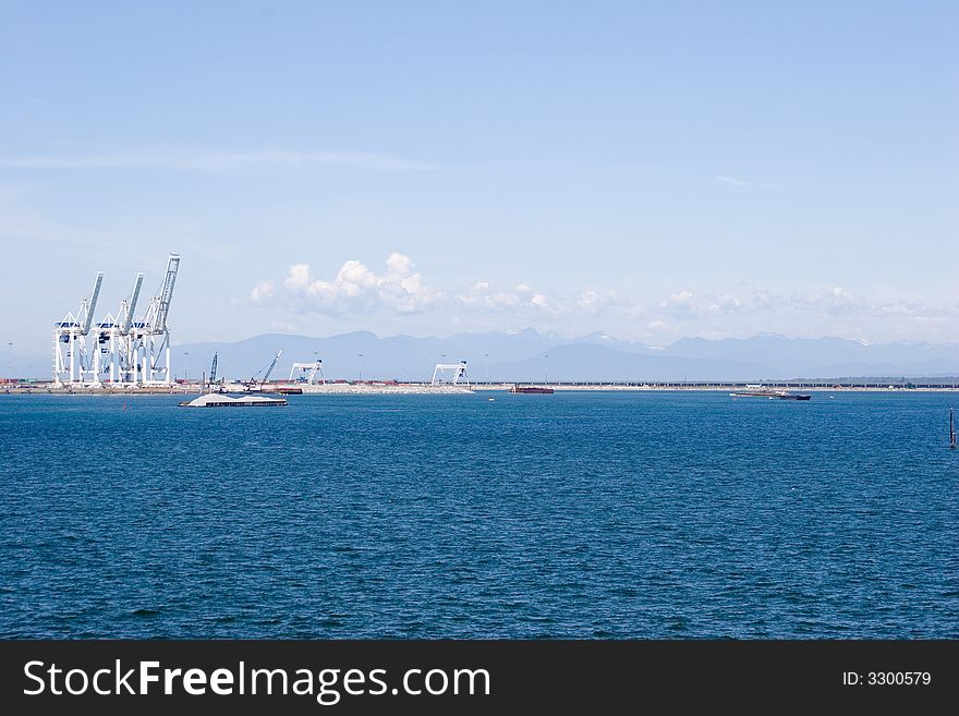 Loading cranes in Vancouver harbor with the mountains and blue sky on the background