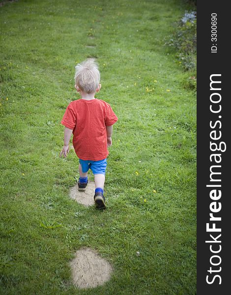 Young boy exploring the garden walking up the step. Young boy exploring the garden walking up the step