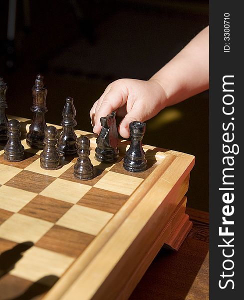 Young child playing chess on traditional wood chess set