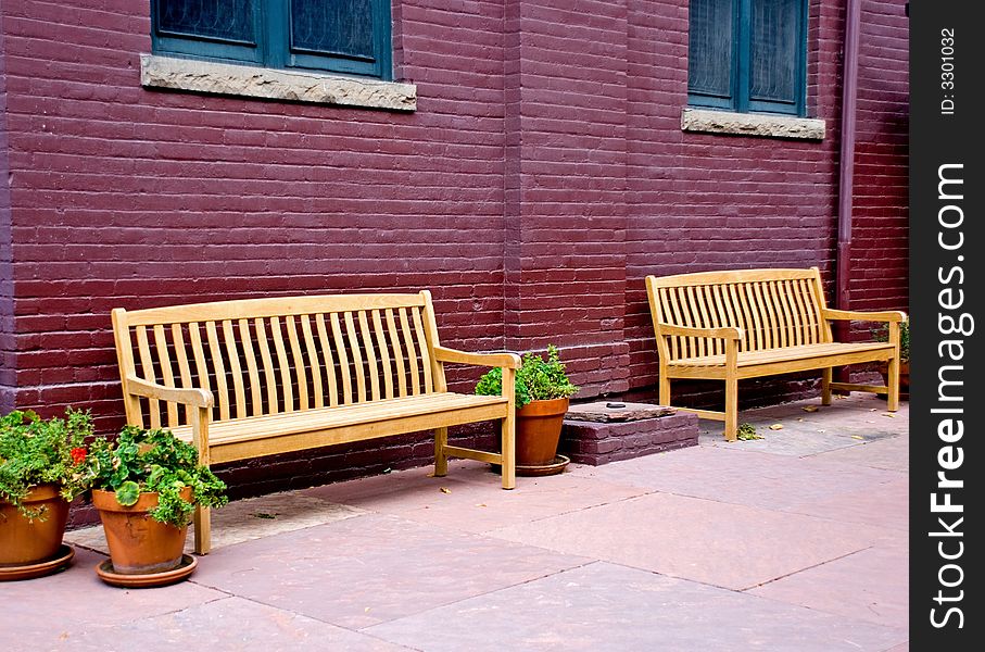 Two empty wooden benches against a brick wall. Two empty wooden benches against a brick wall
