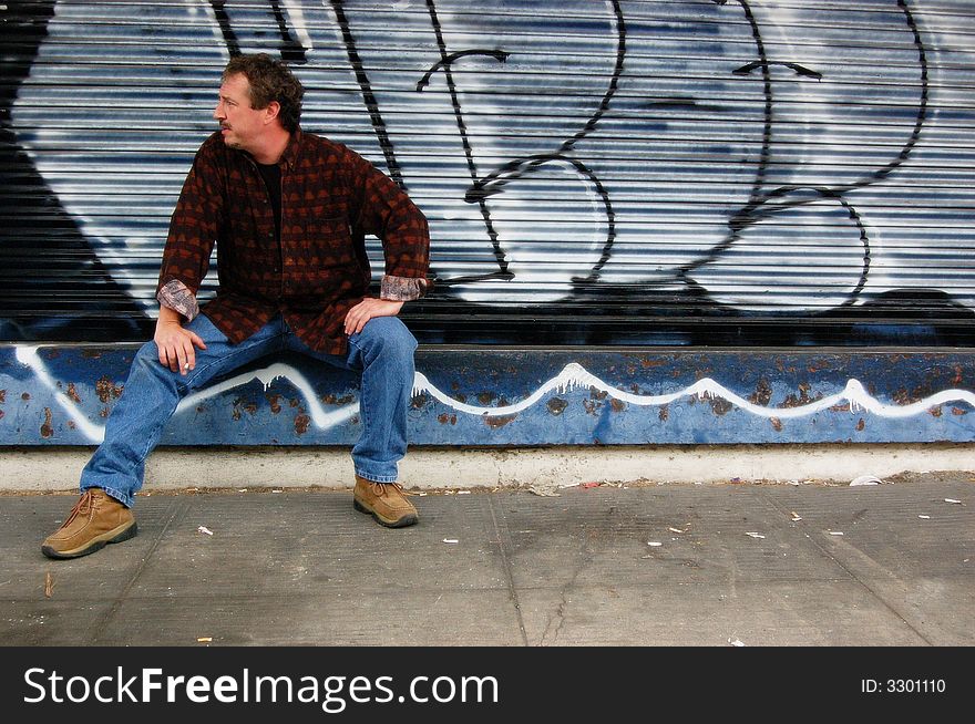 Middle-aged man smoking outside near graffiti. Middle-aged man smoking outside near graffiti