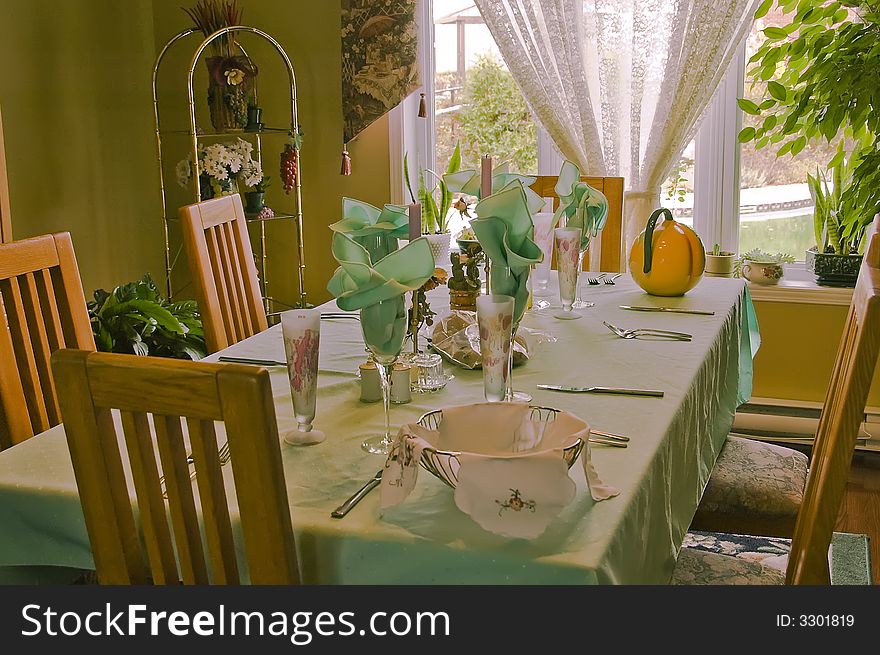 Table setting for a family dinner with green tablecloth and napkins. Table setting for a family dinner with green tablecloth and napkins