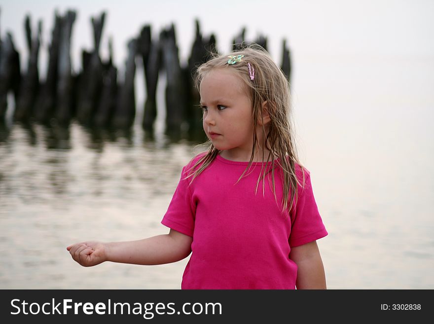 A girl holding a stone in her hand in front of old abandoned bridge in Sventoji (Lithuania) on the coast of the Baltic sea. A girl holding a stone in her hand in front of old abandoned bridge in Sventoji (Lithuania) on the coast of the Baltic sea