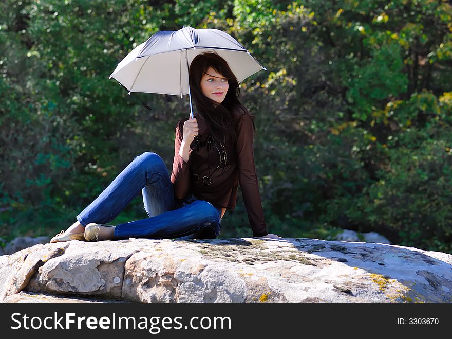 Smilling girl with umbrella on the stone