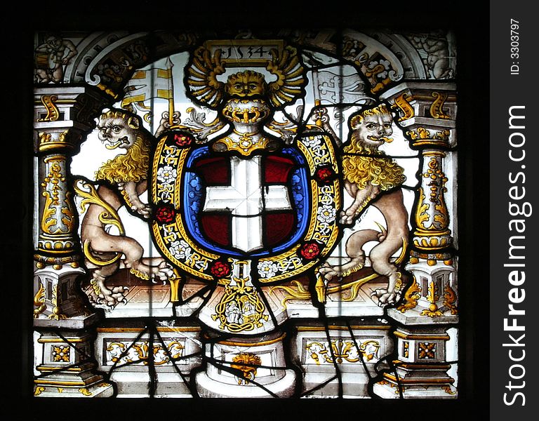 Stained glass found in the castle of Gruyeres. It represents an emblem with a cross in the middle and two stylized lions on the sides.