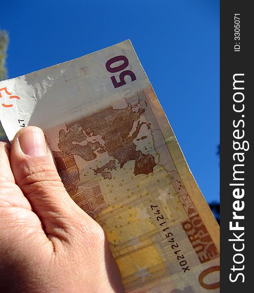 Fifty euros banknote in hand with sky background