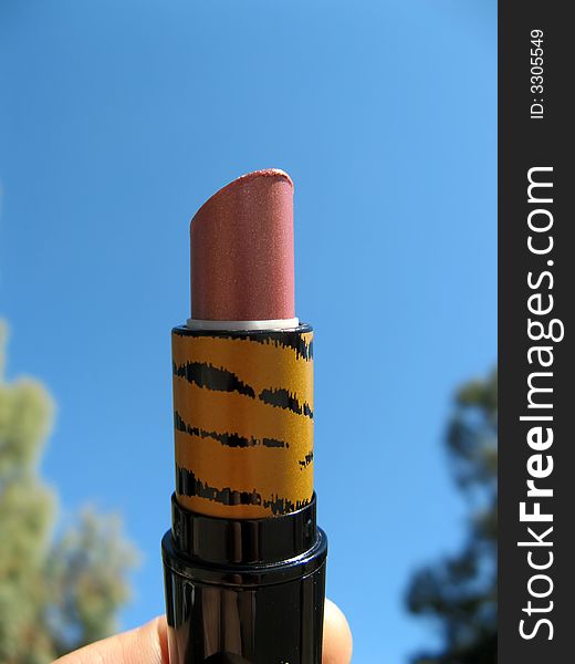 A red used and open lipstick with blue sky background. A red used and open lipstick with blue sky background