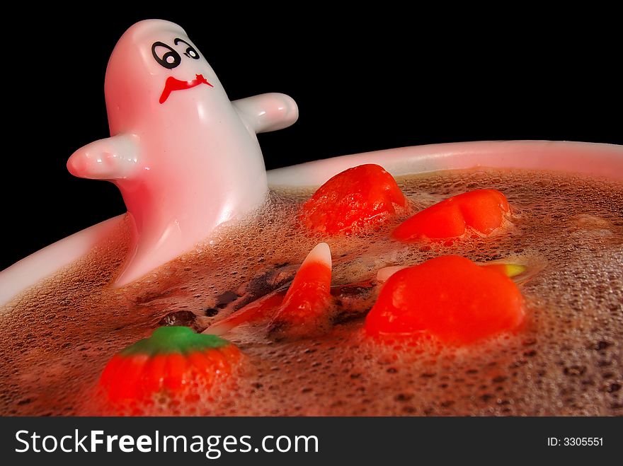 Trick-or-treat!  Close-up of a ceramic dish of a ghost guarding a bath/brew of candy corn on Halloween.  Isolated on black. Trick-or-treat!  Close-up of a ceramic dish of a ghost guarding a bath/brew of candy corn on Halloween.  Isolated on black.