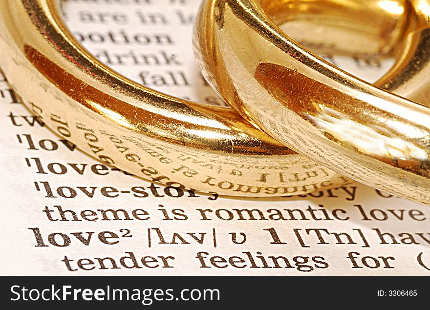 The word wedding out of a dictionary with gold rings next to it. The word wedding out of a dictionary with gold rings next to it