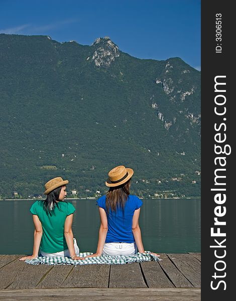 Young woman sitting on a pontoon at the edge of a lake. Young woman sitting on a pontoon at the edge of a lake