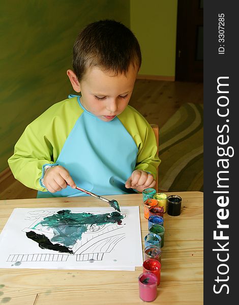 3 years old boy painting a picture with a paintbrush and water colors at a table. 3 years old boy painting a picture with a paintbrush and water colors at a table.