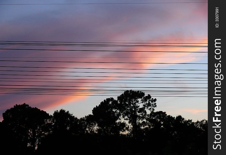 Sunset falls in the evening amidst electrical power lines. Sunset falls in the evening amidst electrical power lines.