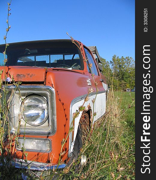 An old rusty truck sitting in the weeds. An old rusty truck sitting in the weeds.