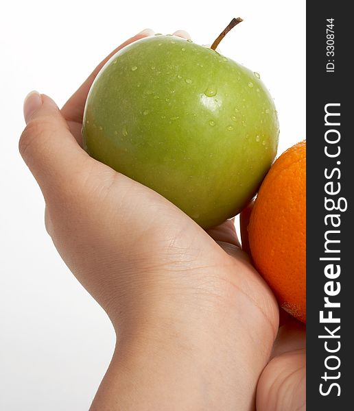 Holding a fresh green apple and an orange over a white background. Holding a fresh green apple and an orange over a white background