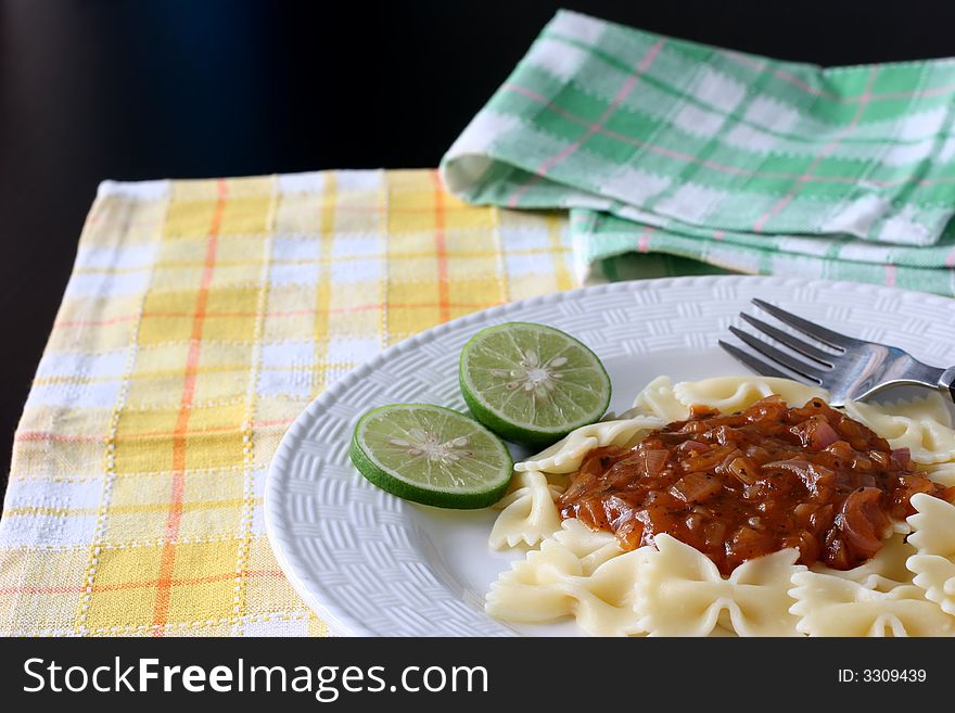 A plate of bow tie pasta with zesty onion and spice gravy