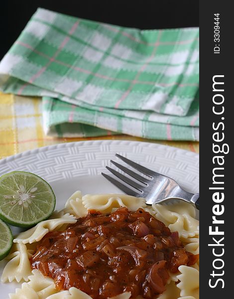 A plate of bow tie pasta with zesty onion and spice gravy