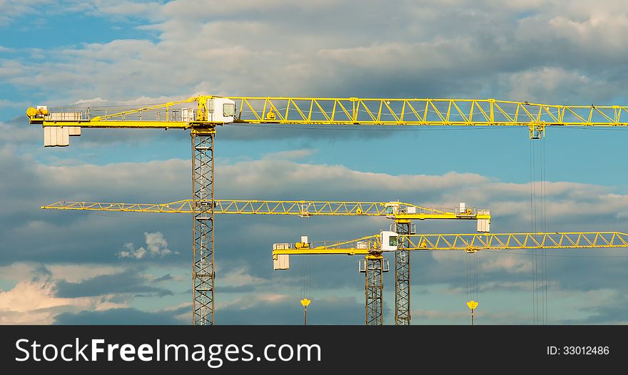 Building construction cranes against the cloudy sky. Building construction cranes against the cloudy sky.