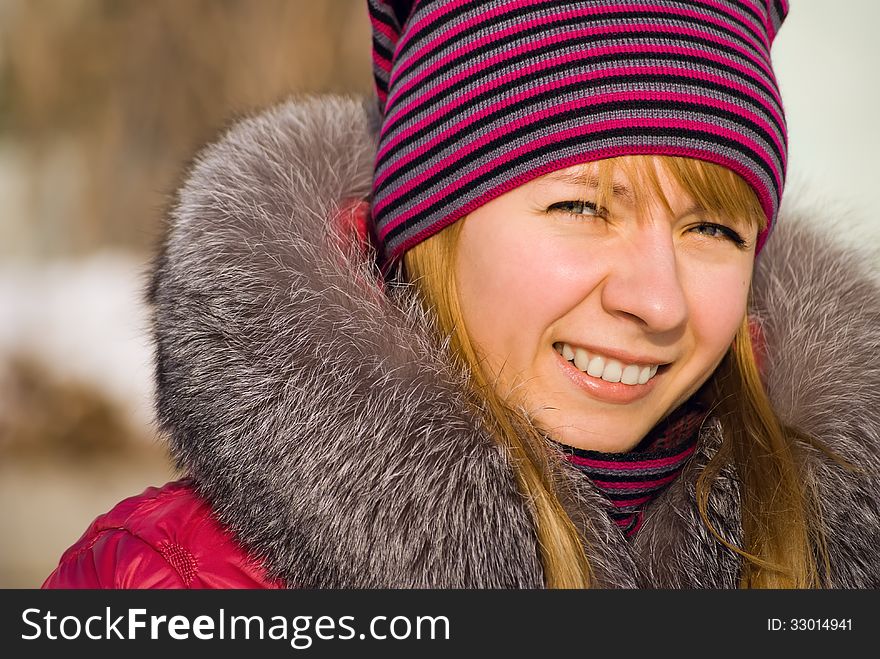 Portrait of smiling girl in knitted cap in wintry park