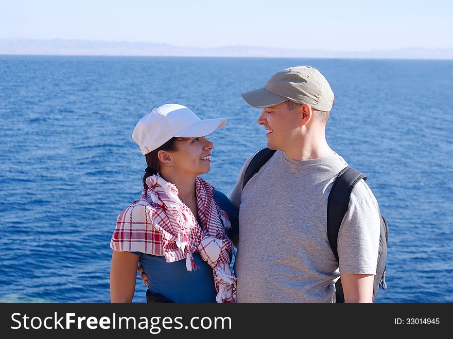 Portrait of happy young women in arabian scarf and men with backpack outside on coast over blue sea and sky. Portrait of happy young women in arabian scarf and men with backpack outside on coast over blue sea and sky