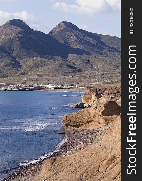 View looking across La Isleta Bay within Cabo de Gata Natural Park in Andalusia, Spain with the peaks of two extinct volcanoes in the background. View looking across La Isleta Bay within Cabo de Gata Natural Park in Andalusia, Spain with the peaks of two extinct volcanoes in the background