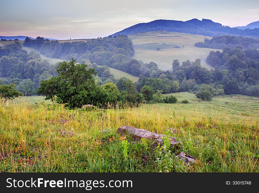 Stones on a glade at the foot of mountain in fog. Stones on a glade at the foot of mountain in fog