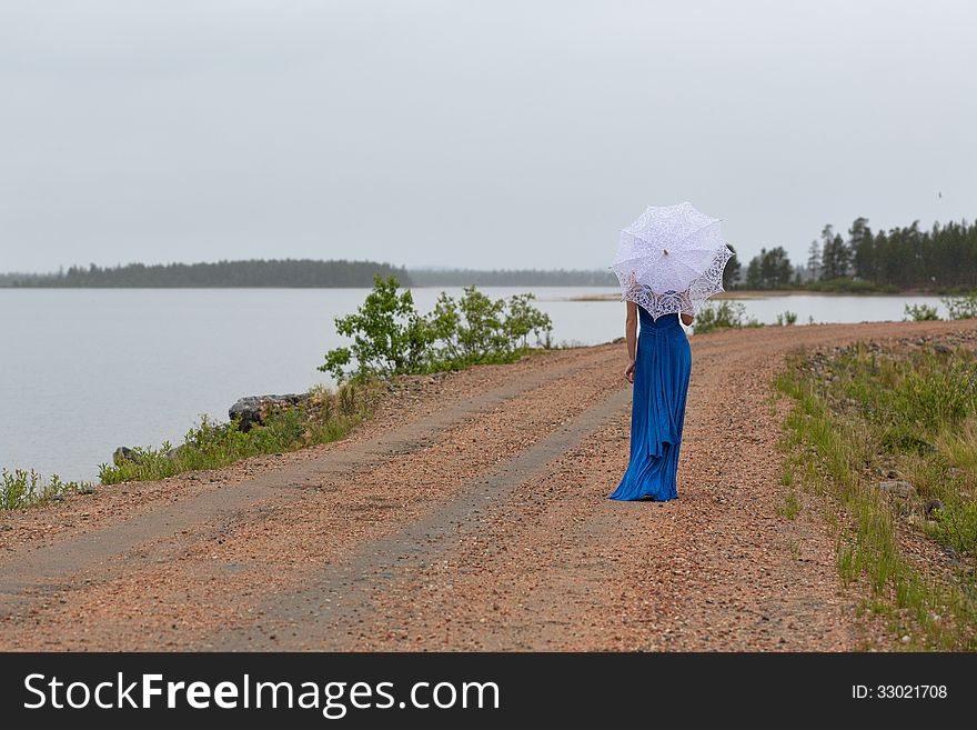 Slim girl in a dress with an umbrella in a forest