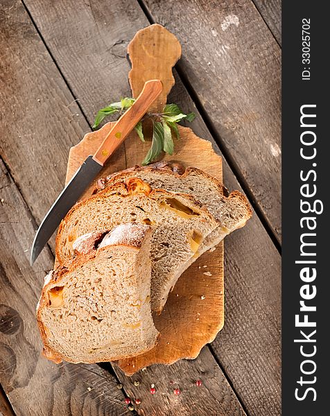 Bread with knife on a cutting board and wooden background