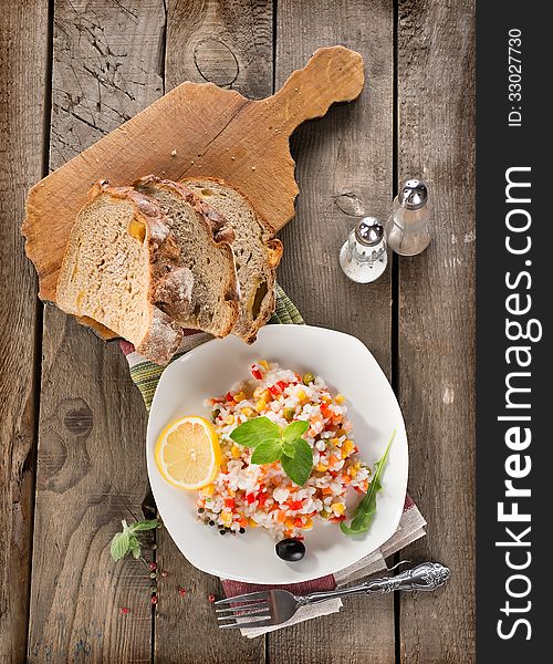 Risotto with vegetables and bread on a wooden background