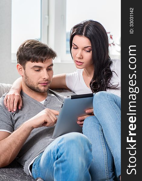 Young couple sitting on the couch with tablet computer. Young couple sitting on the couch with tablet computer