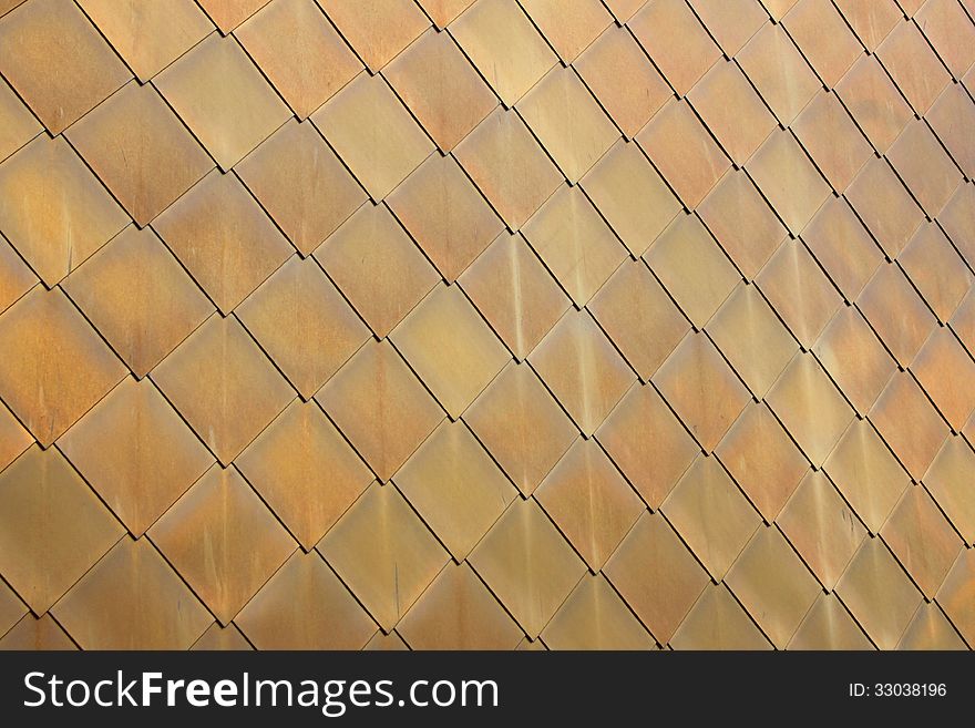 Gold or brass coloured diamond-shaped metal scales on a modern building. Gold or brass coloured diamond-shaped metal scales on a modern building.